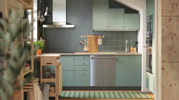 A kitchen has base and wall cabinets with matt grey-green NICKEBO fronts and a RESARÖ mobile drop-leaf table with storage.