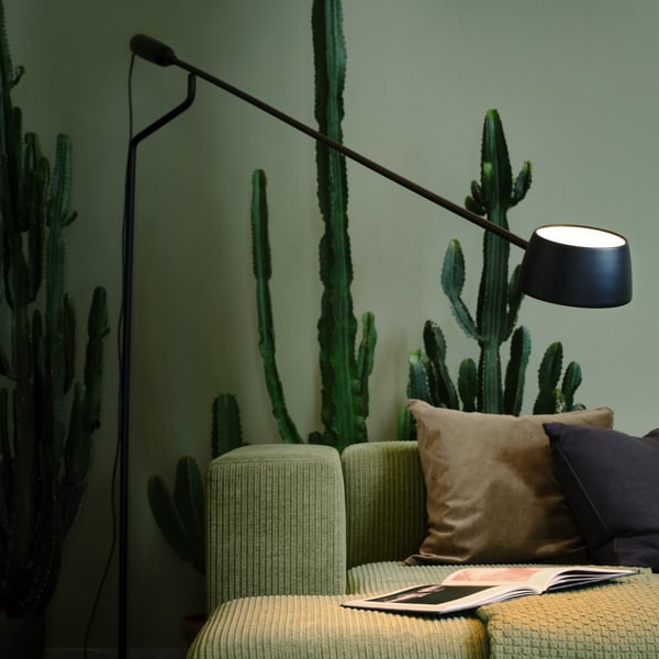 En dimbar svart VÅGHÖJD LED-golvlampa i ett grönt vardagsrum.

