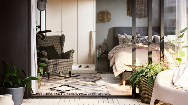 Schlafzimmer mit Lesesessel STRANDMON und einem weißen PAX Kleiderschrank.