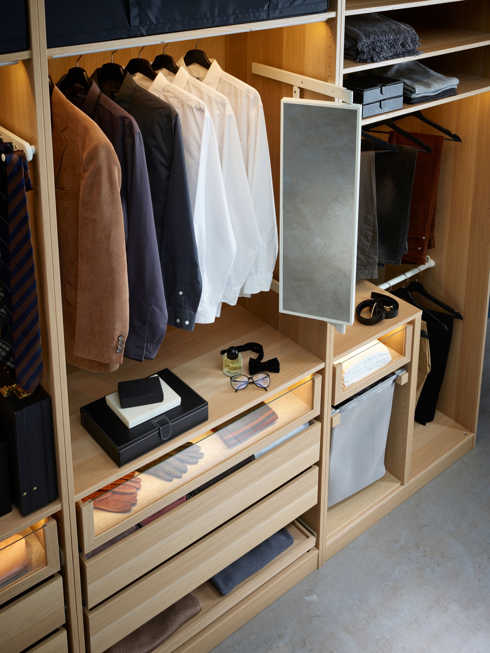 Garderober od svetlog drveta ispunjen odećom na policama, ali i na vešalicama.