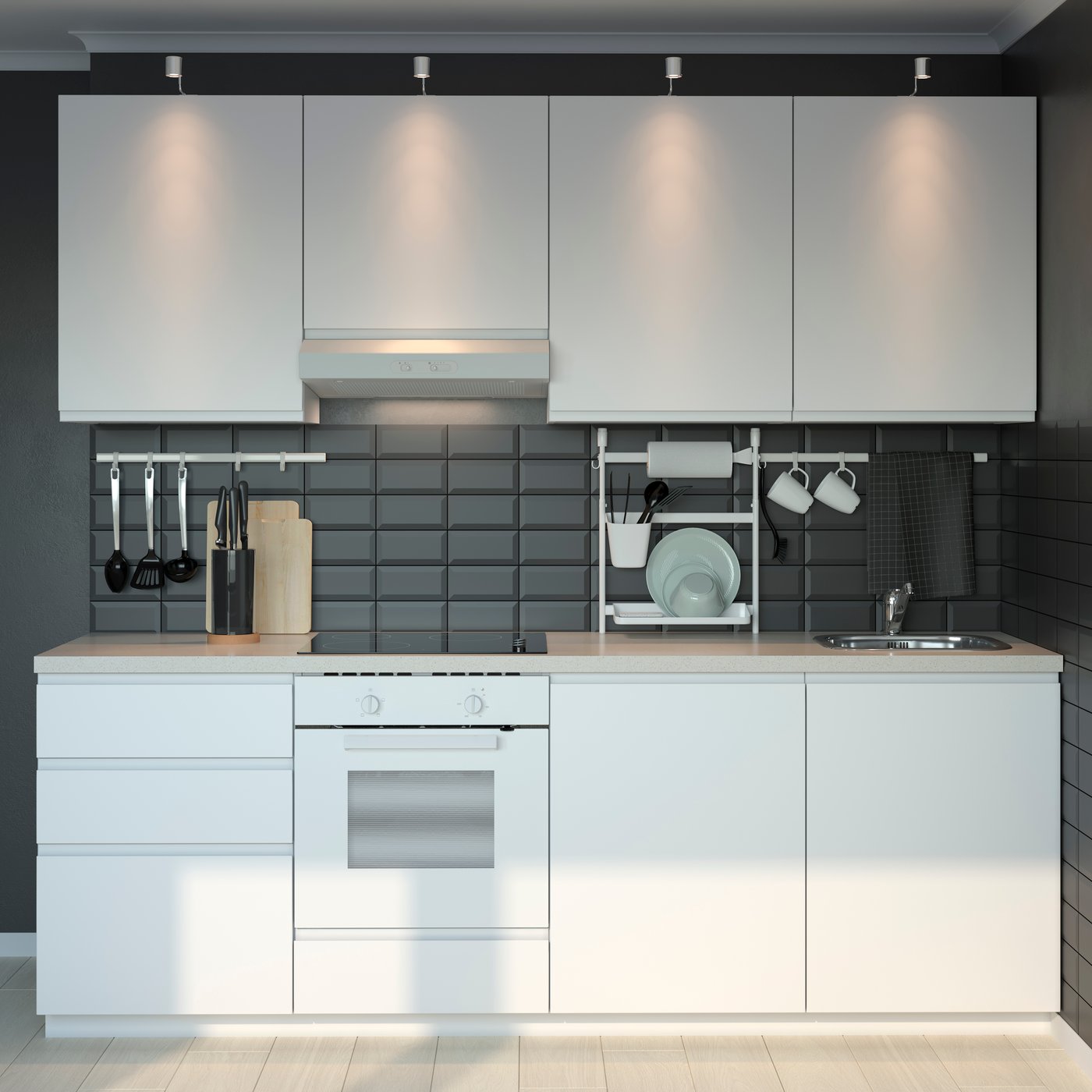 Schmale IKEA KNOXHULT Küche mit glatten, weißen Fronten und heller Arbeitsplatte vor dunkler Fliesenwand, mittig ein weißer Einbaubackofen mit Dunstabzug, darüber Spots; Küchenutensilien und Geschirr hängen ordentlich an Relingsystemen.