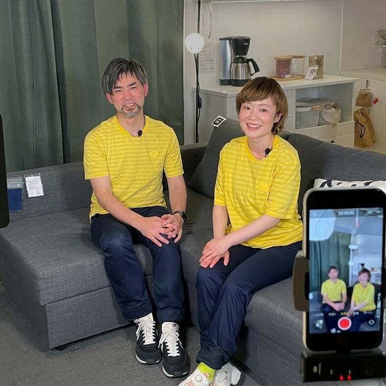 黄色いシャツを着た2人がソファに座っている