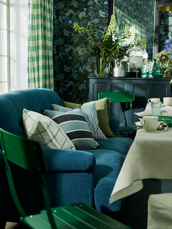 En blå soffa i traditionell stil i vardagsrum med blåblommiga tapeter. 