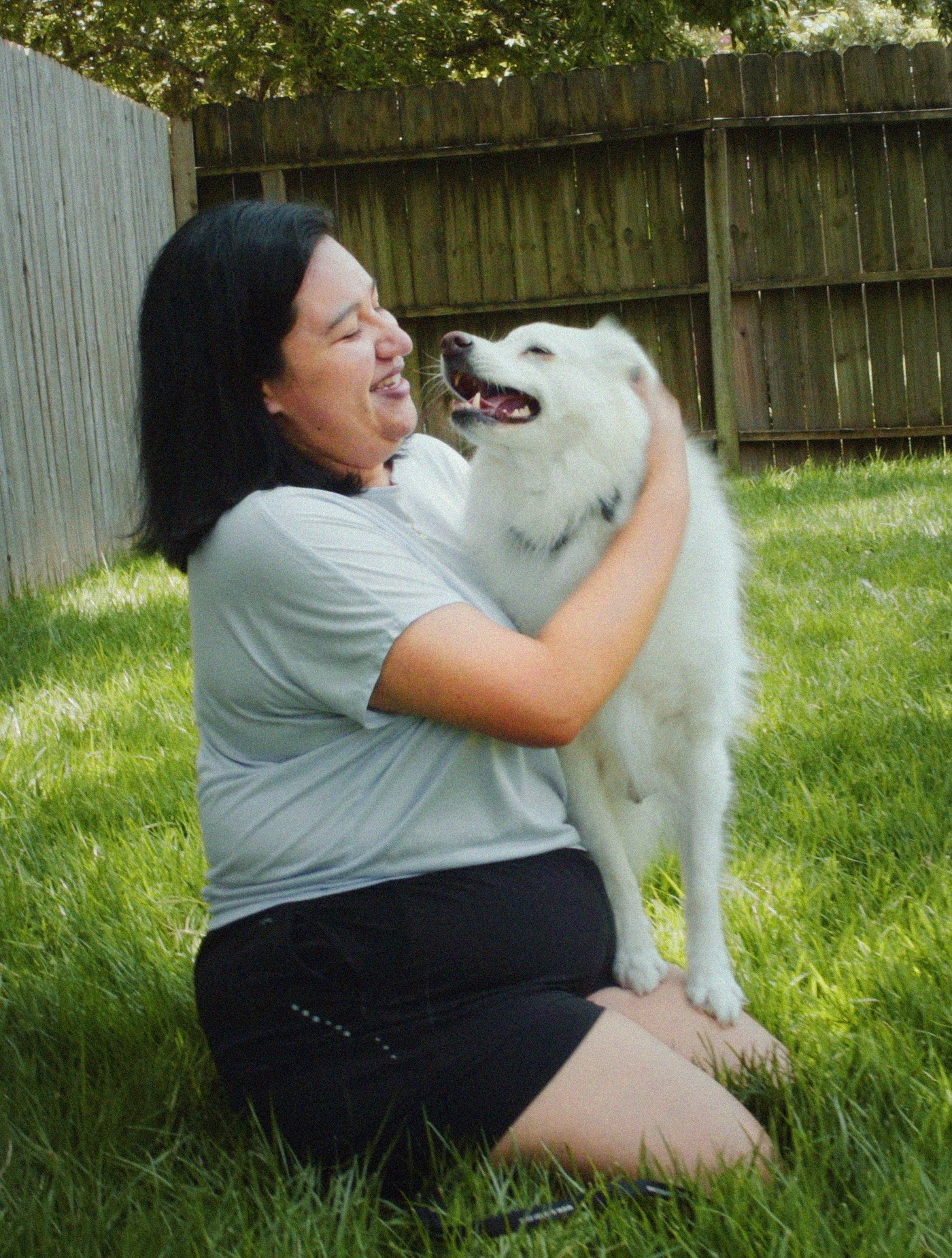 Woman playing with her white dog in her garden.