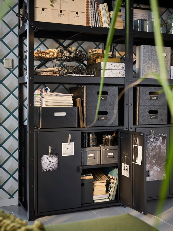 IKEA BROR powder-coated galvanized steel black shelving unit, with boxes and organizers placed on its 3 shelves.