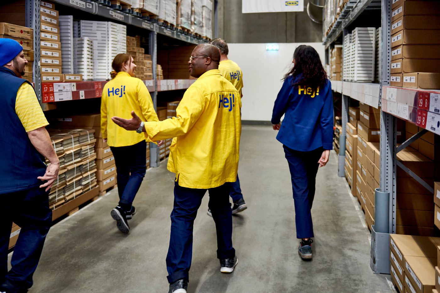 Un grupo diverso de colaboradores/as de IKEA camiñando polo departamento de autoservizo dunha tenda IKEA.