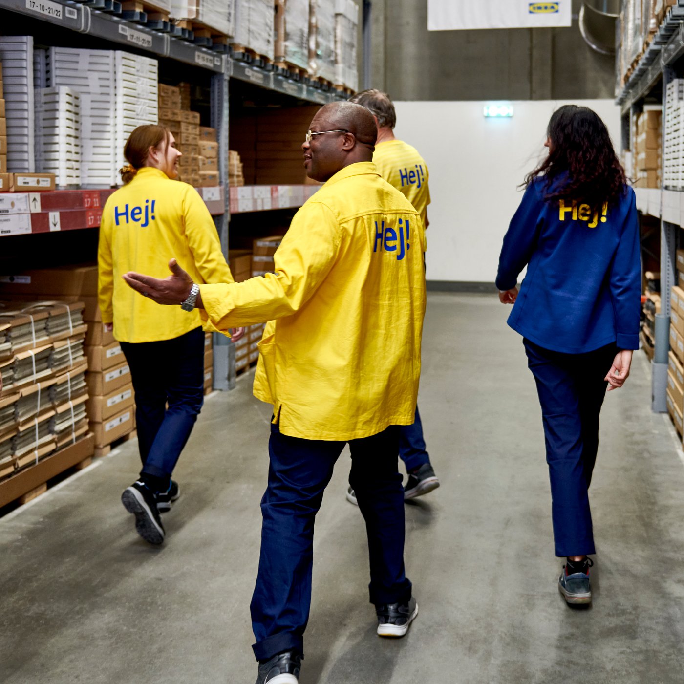A diverse group of IKEA co-workers walking through the self service department of an IKEA store.