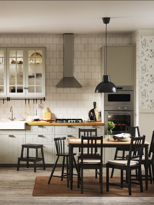 Kitchen setting featuring a dining table, pendant lamp, multiple chairs, a junior chair, a step stool, and cabinets.