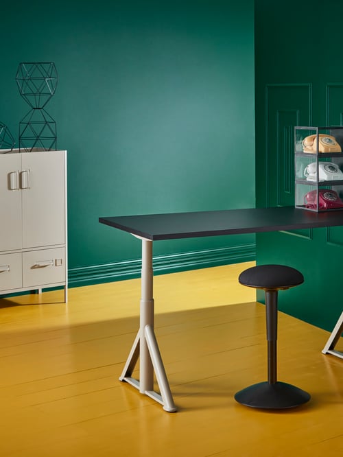Workspace with adjustable desk, standing support, storage cabinet, pendant lamp shades, glass shelves, coloured telephones.
