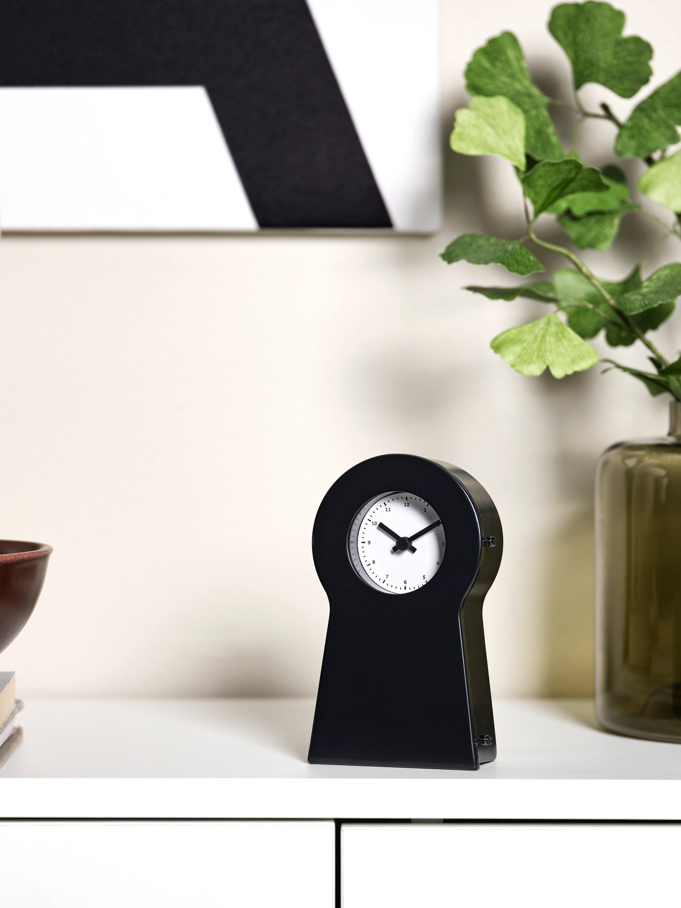 Eine schwarze IKEA PS Standuhr ist auf einem Sideboard zu sehen.