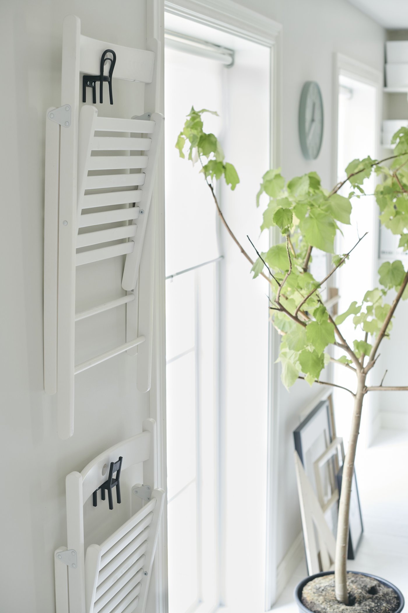 zwei weiße Klappstühle hängen an einem Haken an der Wand