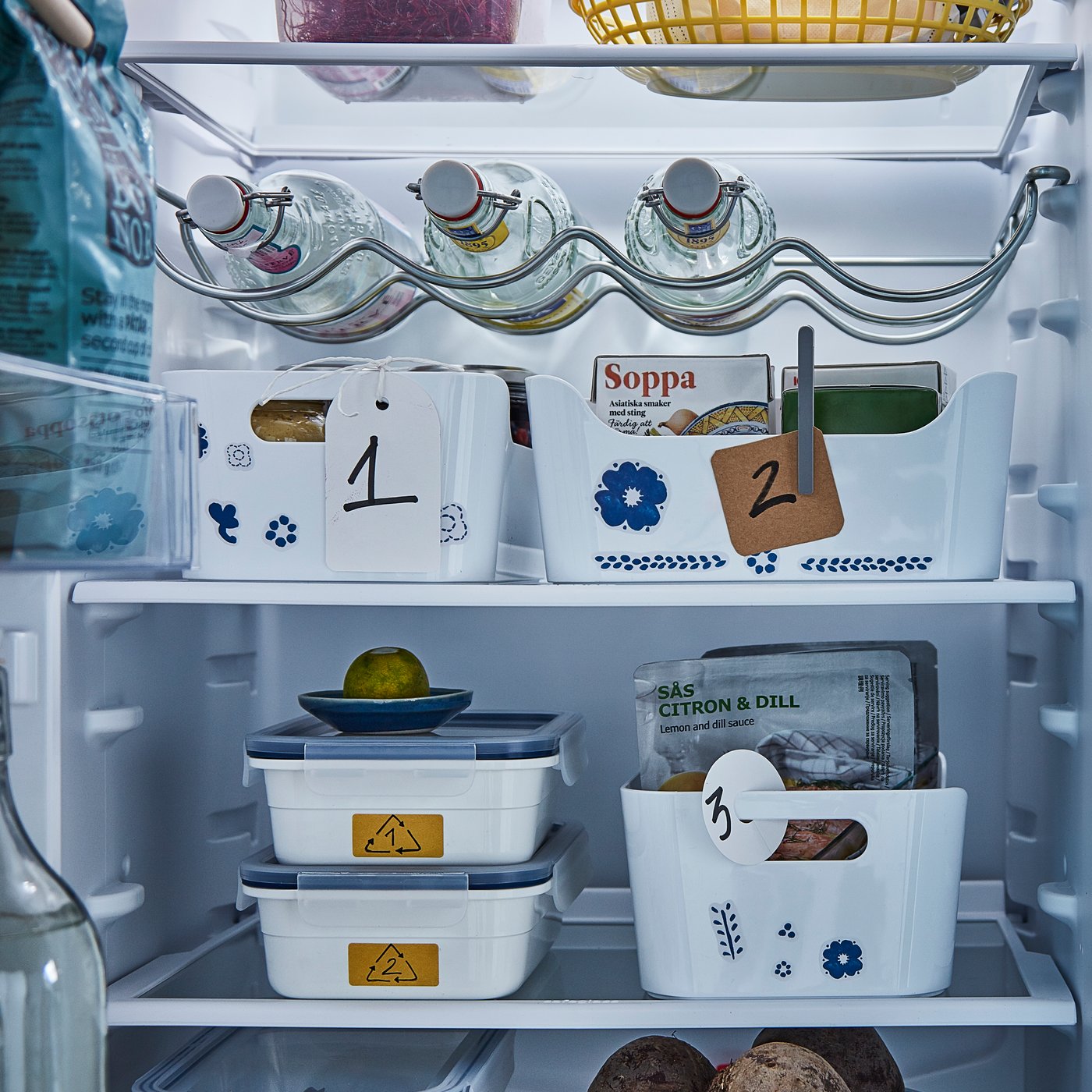 Das Innere eines Kühlschranks mit unterschiedlichen Boxen, an denen Etiketten befestigt sind.