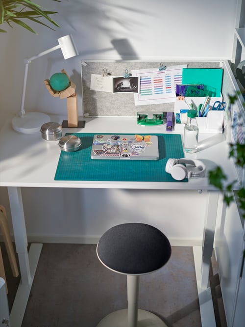 Un TROTTEN așezat/în picioare TROTTEN și NILSERIK scaun NILSERIK sunt pregătite pentru studiu. În partea de sus se află un laptop, o lampă de lucru, căști și accesorii