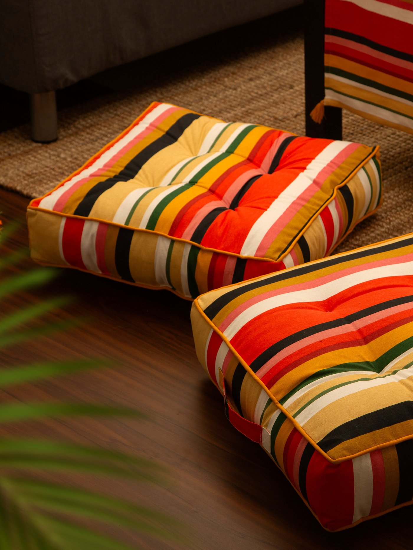 Dwie poduszki podłogowe w paski z kolekcji AROMATISK leżące na dywanie.
