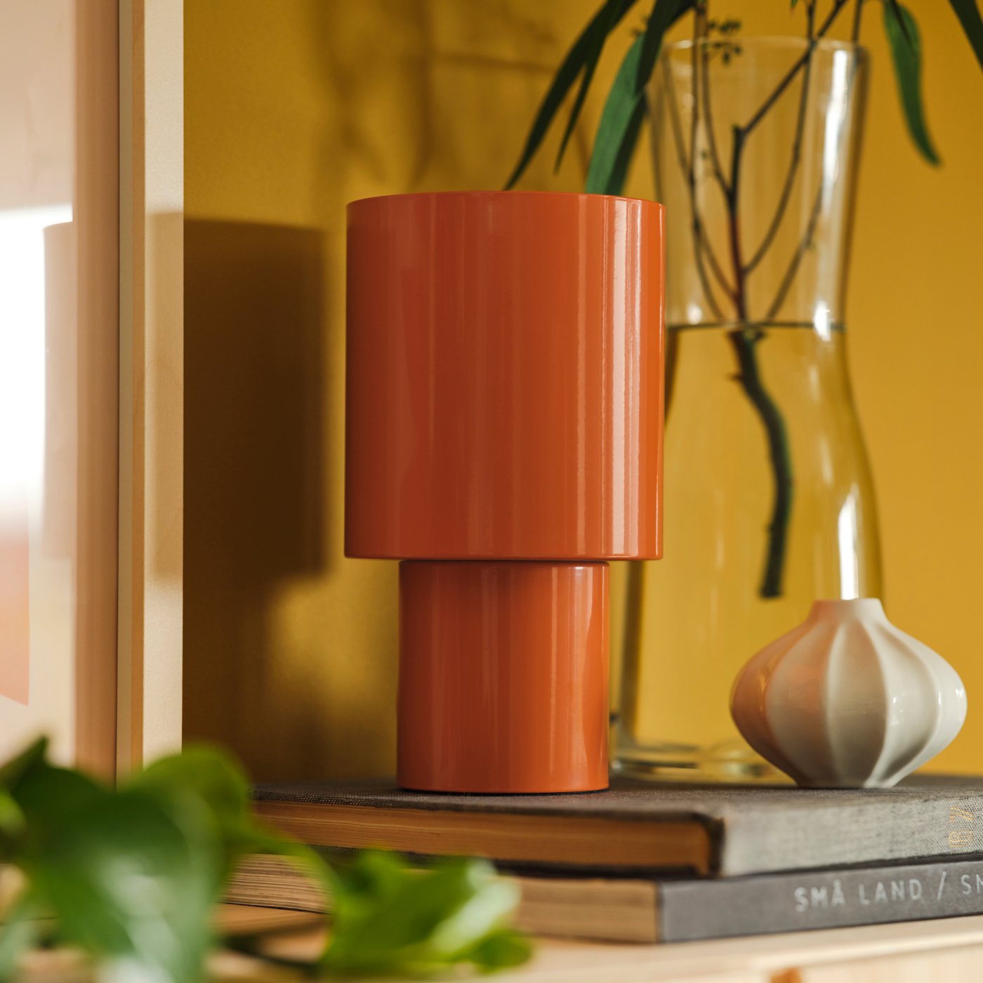 Orange SPETSBOJ table lamp next to glass and ceramic vases.