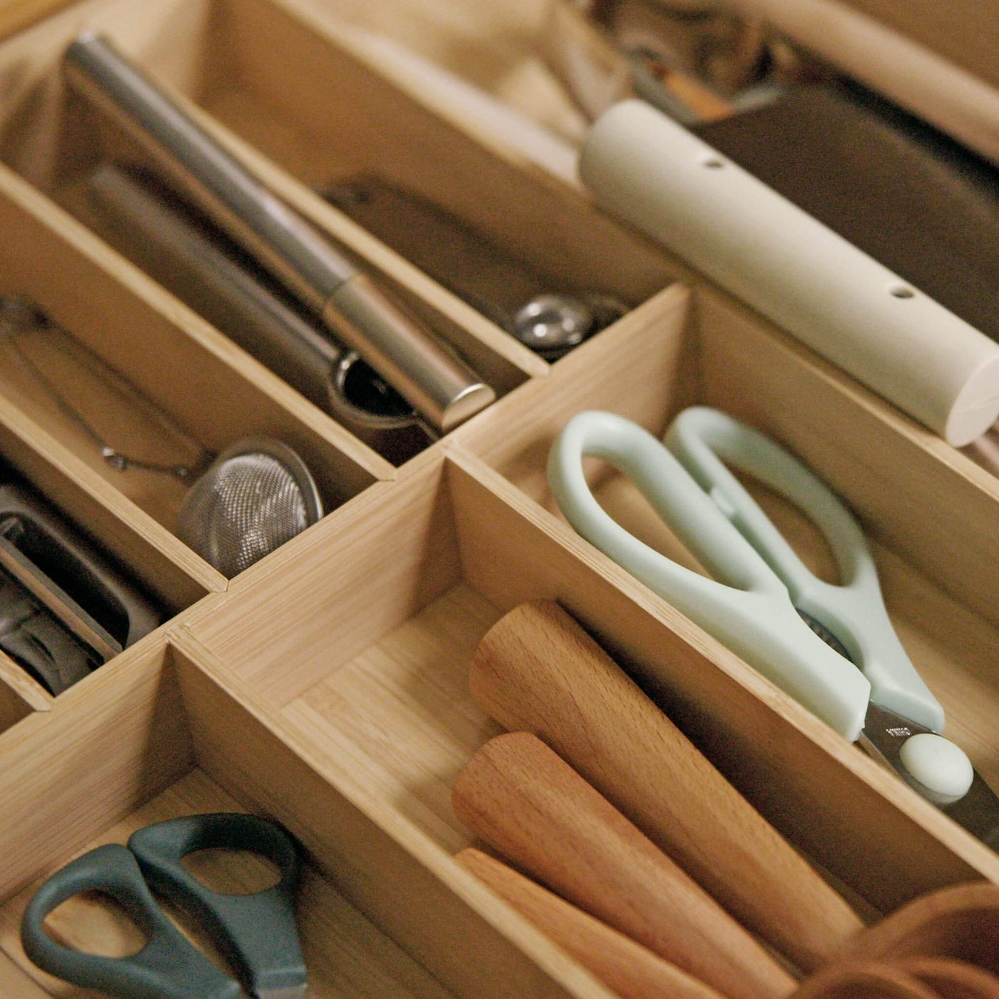Drawer organizer holding scissors, utensils, and small kitchen tools.