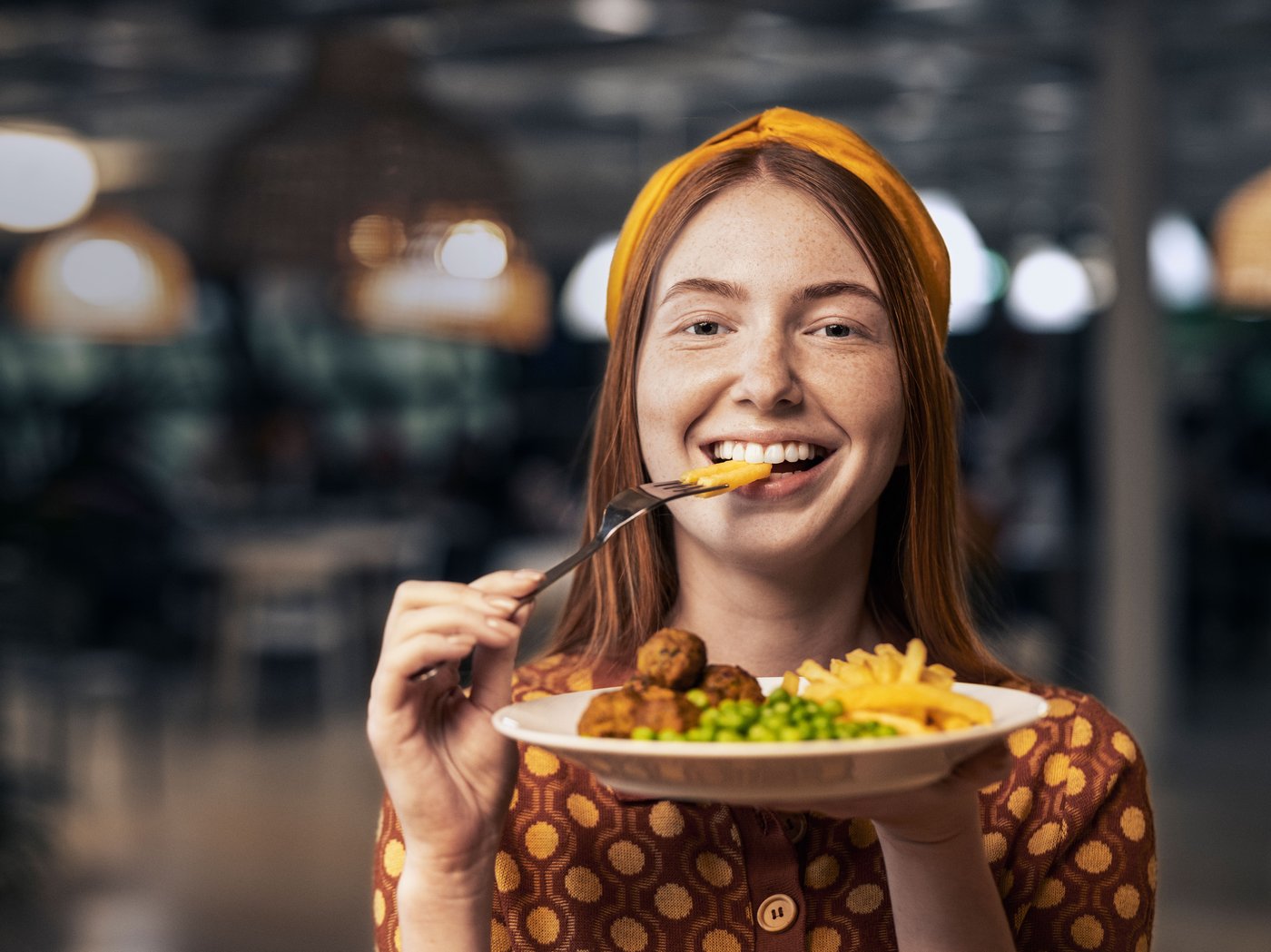 Sardexka batekin haragi-bola suediar plater bat jaten ari den neska bat ikusten da, kamerari irribarrez dagoela.