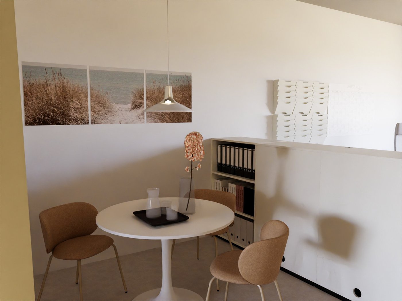 Teil eines Büros. Blick auf einen Tisch mit dekorativen Gegenständen, einer Hängeleuchte und drei Stühlen. An der Wand hinter dem Tisch Bilder. Neben dem Tisch ein niedriger Raumteiler mit Aufbewahrung. An der Wand auf der anderen Seite des Raumteilers Zeitschriftensammler.