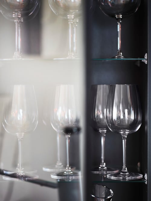 Cameră de luat masa cu mai multe pahare de vin STORSINT albe amplasate în interiorul unui corp înalt BOASTAD bej.