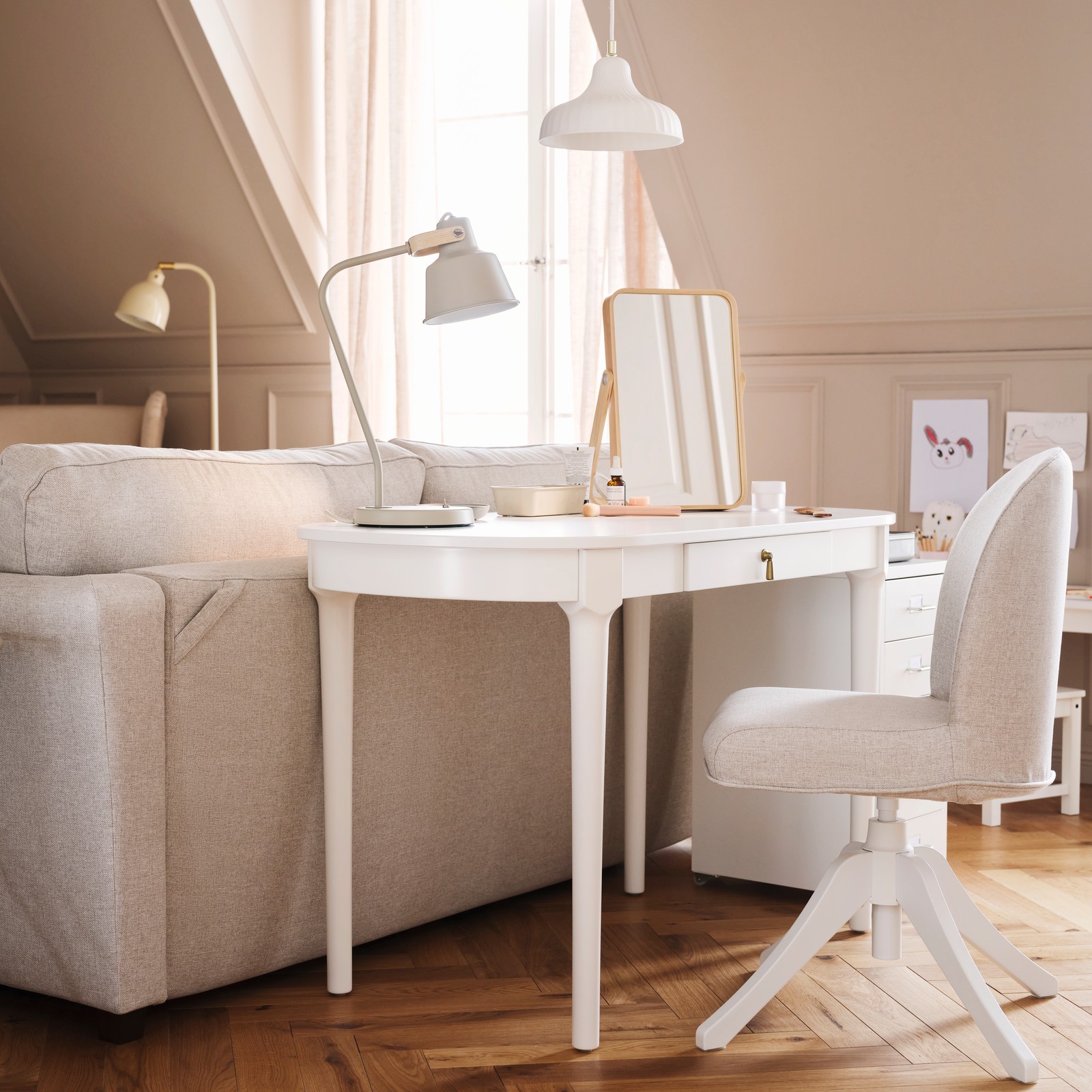A white ROSENTORP desk and a ROSENTORP swivel chair stand behind an EKHOLMA 2-seat sofa-bed in a multipurpose living room.