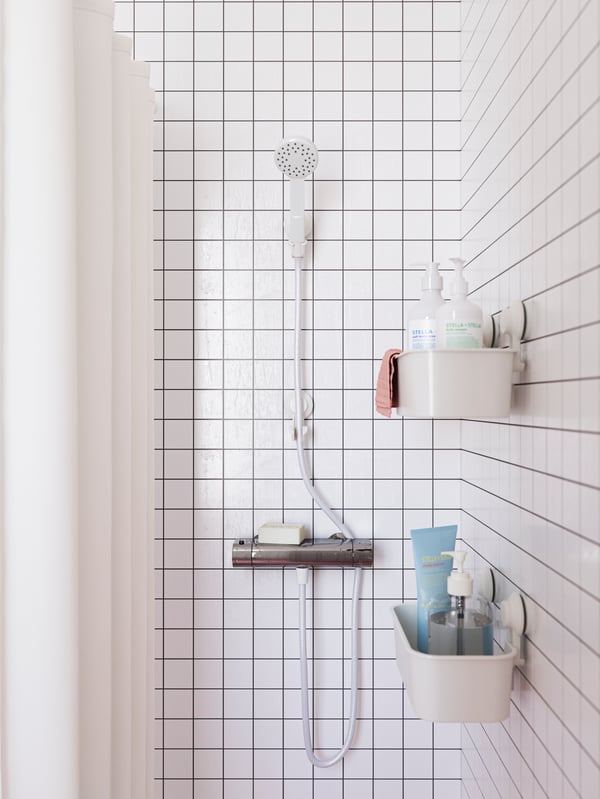 Blick auf eine weiß gehaltene Dusche mit modernen Badarmaturen.