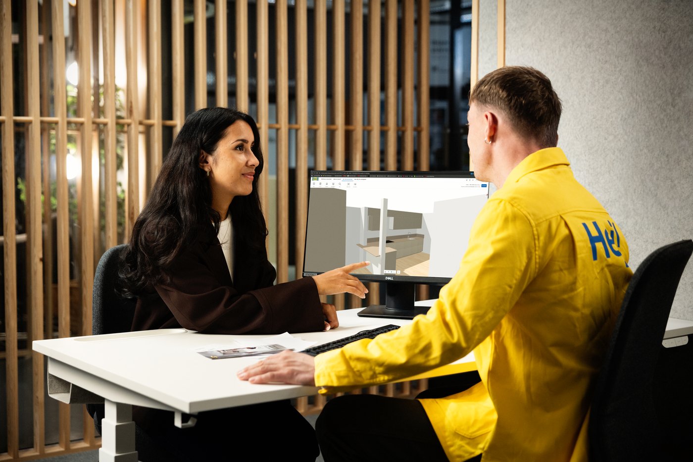 A customer and an IKEA coworker sit at a desk in an IKEA store, planning a kitchen layout together during an in‑store consultation.