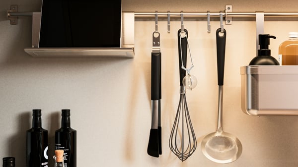 Zoom a una barra de la serie KUNGSFORS con diferentes artículos de cocina y repisas colgando de ella.