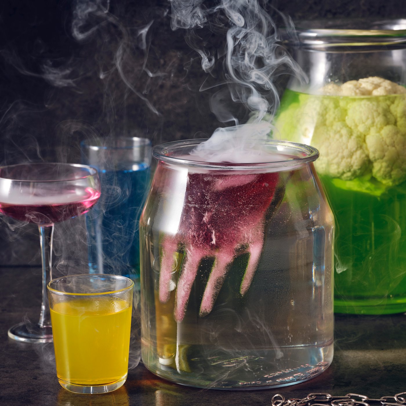 Colourful cocktails including a spooky punch made with DRYCK FLÄDER elderflower syrup and a red hand floating on top.