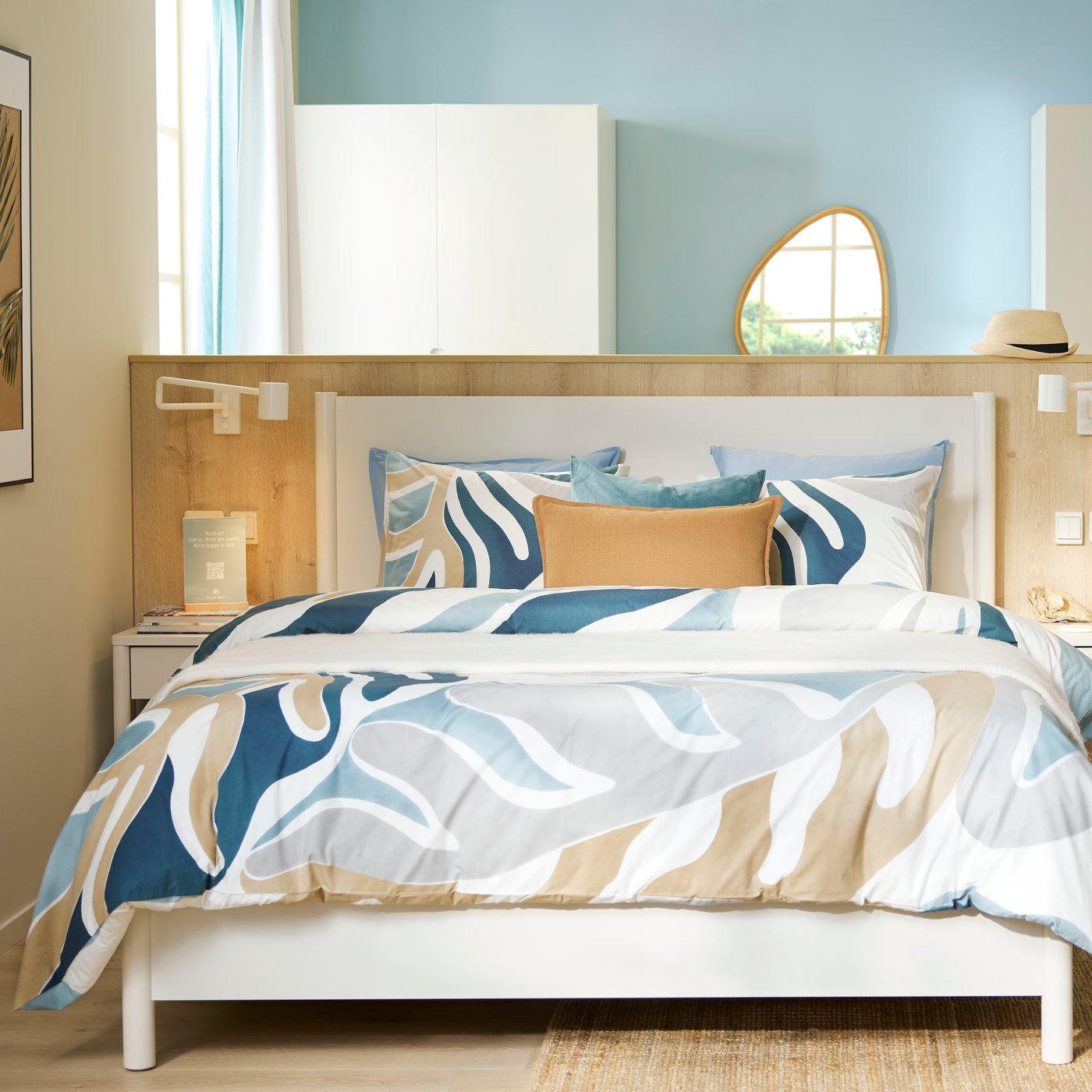 Et rummeligt hotelværelse med en strandagtig stemning, hvor væggene er beige og lys blågrønne med et offwhite TONSTAD sengestel midt i rummet.