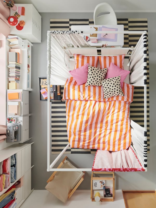 Vue en plongée sur une chambre avec lit à baldaquin VITARNA au centre, agrémenté de linge de lit SLÅNHÖSTMAL rose/orange.