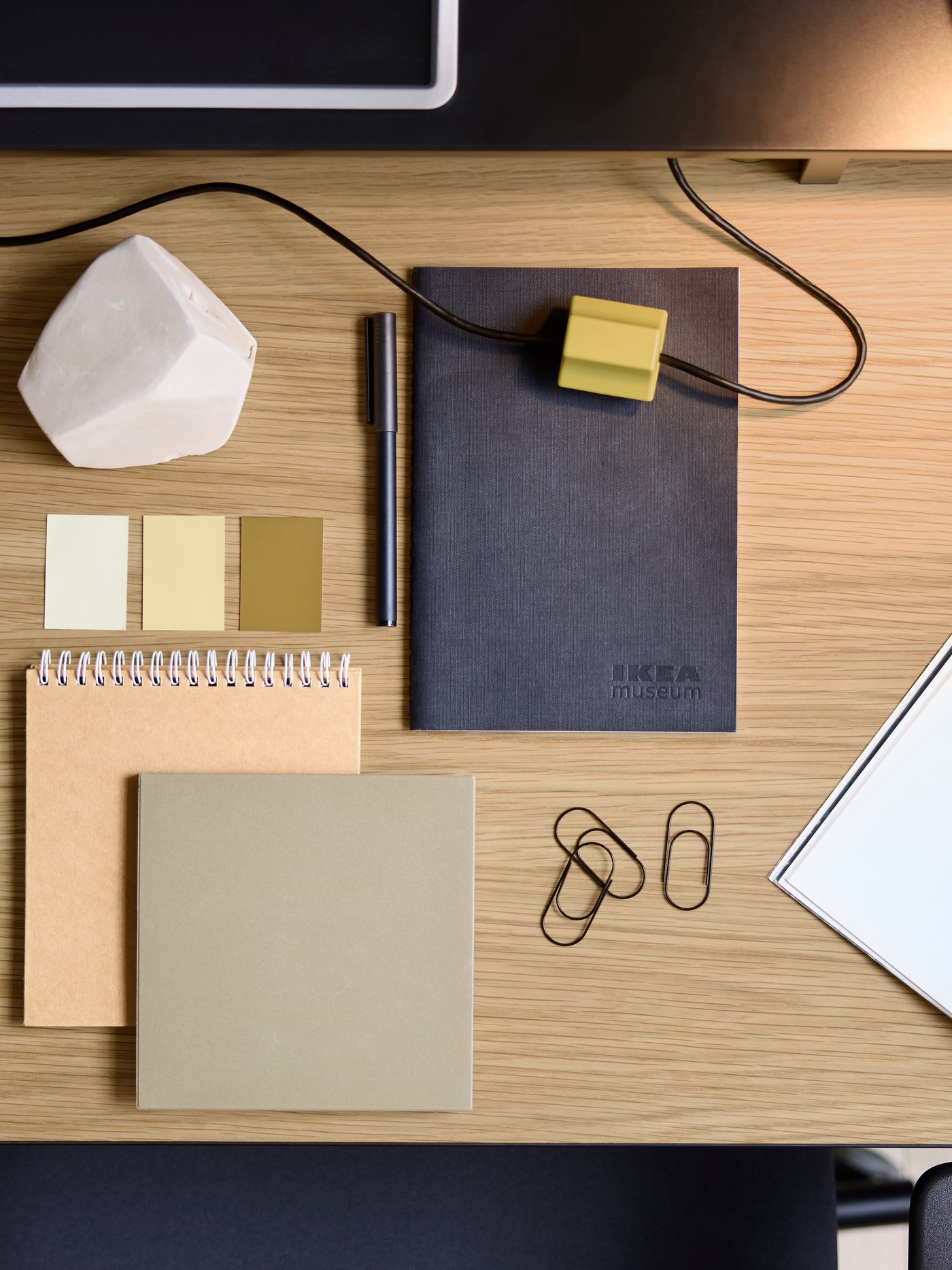 An aerial view of a MULLSJÖ desk with an oak desk top and several notebooks and paperclips.