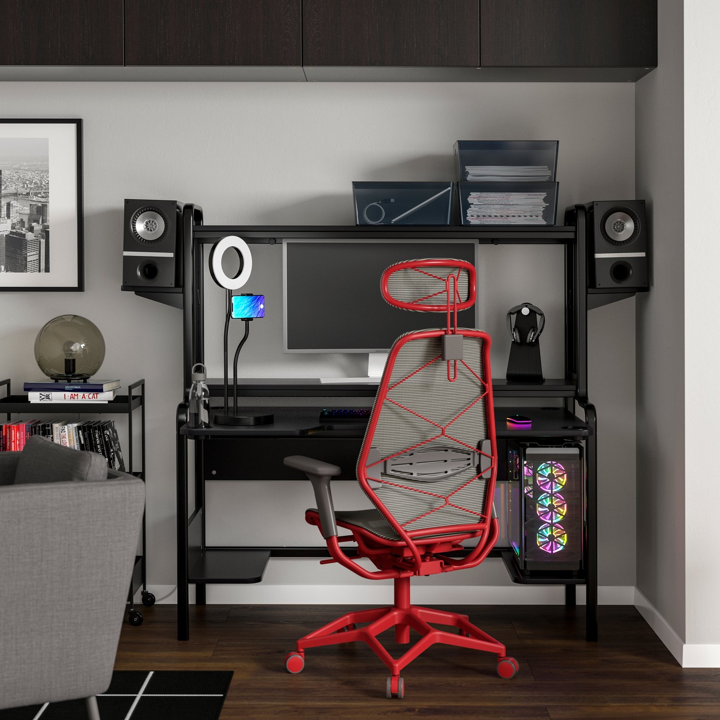 Modern gaming desk setup with monitors, speakers, ring light, and a bright red ergonomic chair.