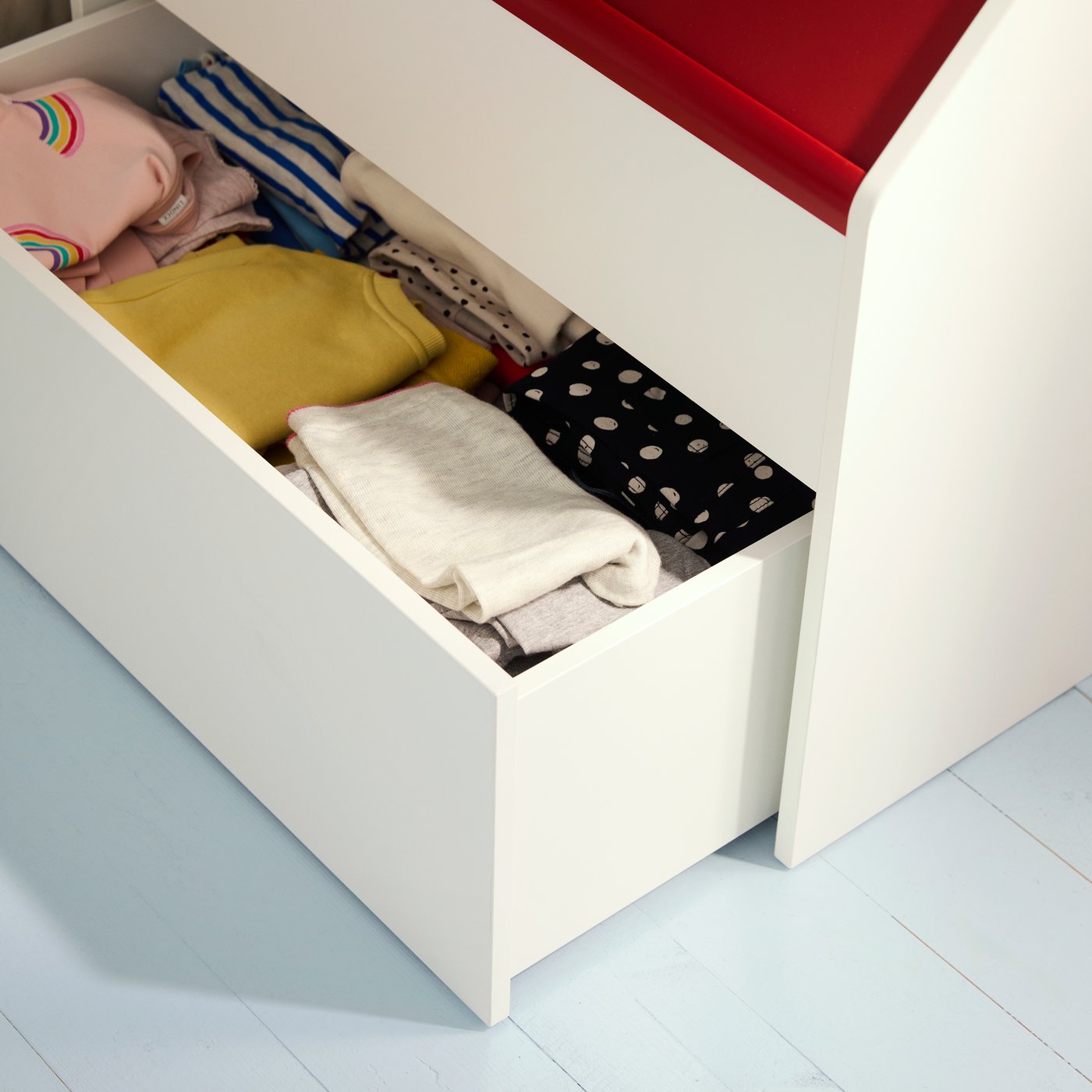 Close-up of the VITBJÖRN storage unit with the bottom drawer pulled out to show neatly folded clothes inside.