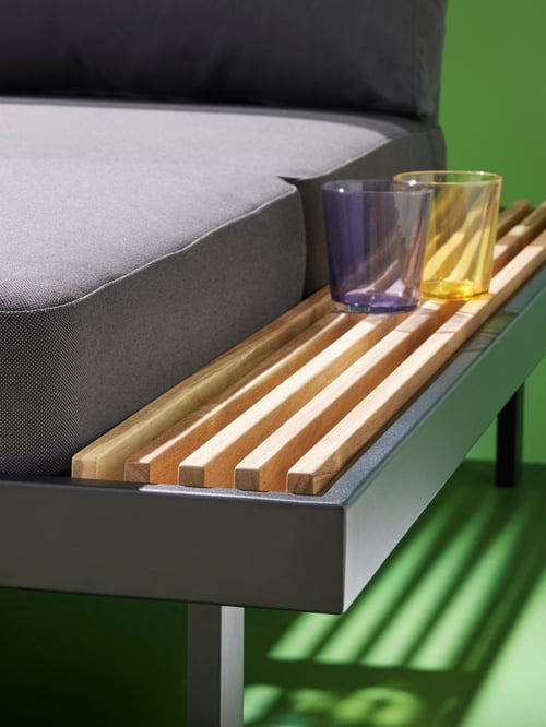Close-up of the edge of a three-seat REVSKÄR conversation set, with two glasses placed on the integrated surface.