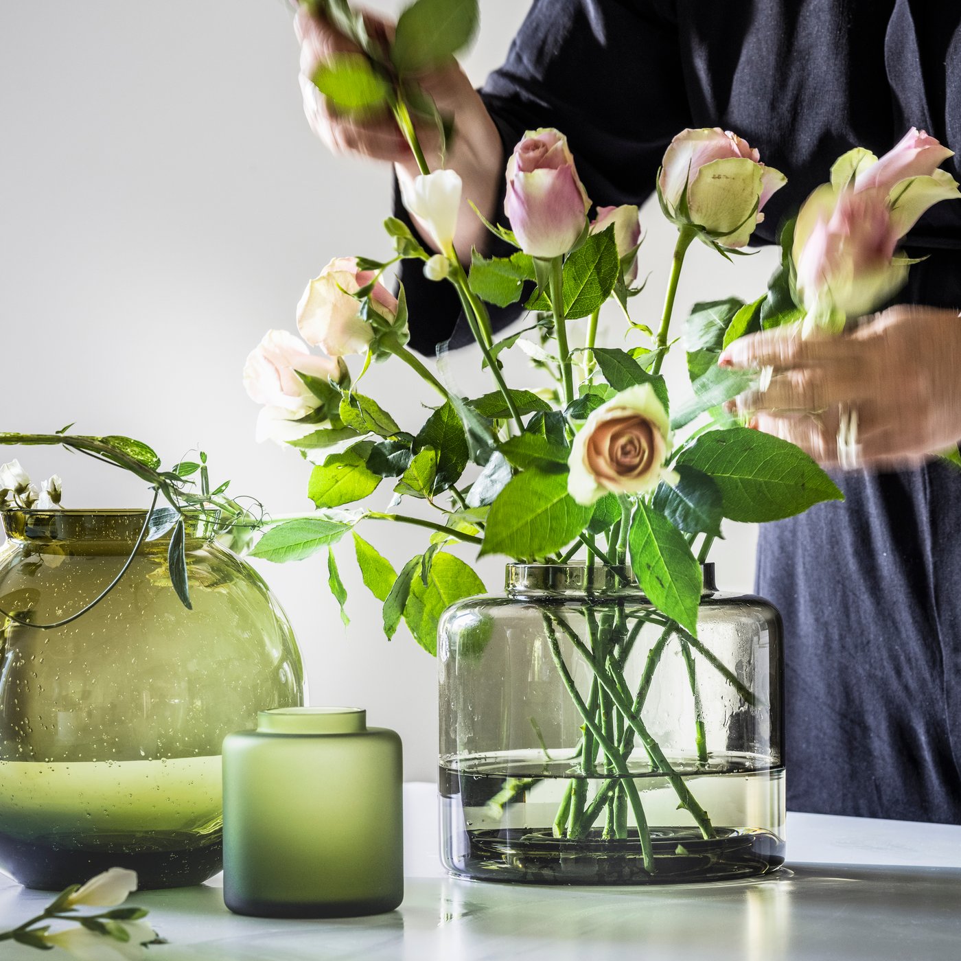 Henkilö asettelee ruusuja KONSTFULL-maljakkoon.