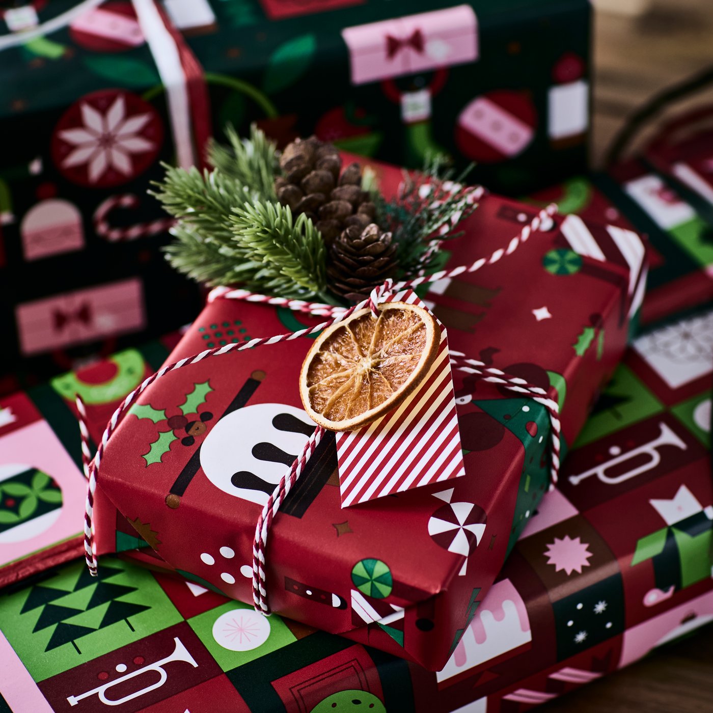 Festively wrapped Christmas gift with pinecones, greenery, twine, and a dried orange slice.