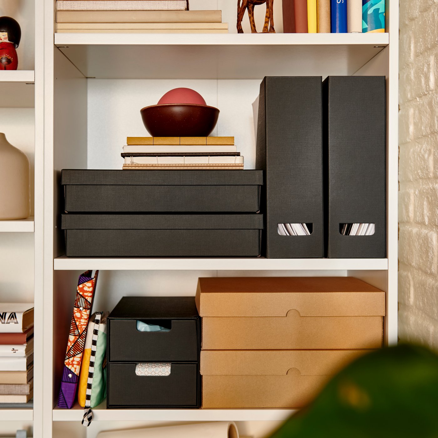 An anthracite FJÄDERHARV magazine file on a shelf, alongside decorative boxes and books in a well-organised space.