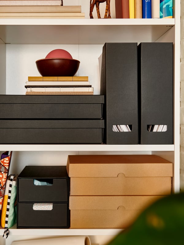 An anthracite FJÄDERHARV magazine file on a shelf, alongside decorative boxes and books in a well-organised space.