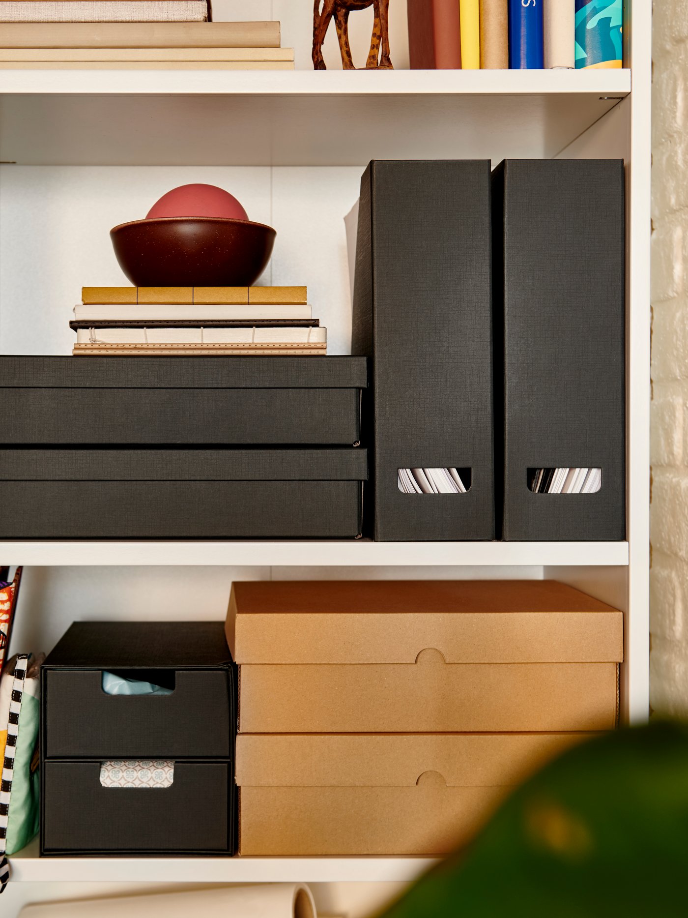 An anthracite FJÄDERHARV magazine file on a shelf, alongside decorative boxes and books in a well-organised space.