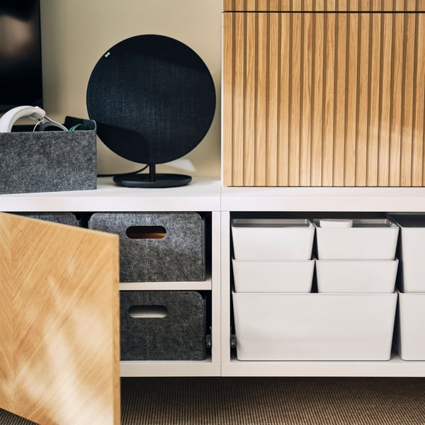 A wall-mounted BESTÅ storage combination, fronts open to reveal neatly arranged BESTÅ felt boxes and white KUGGIS boxes.
