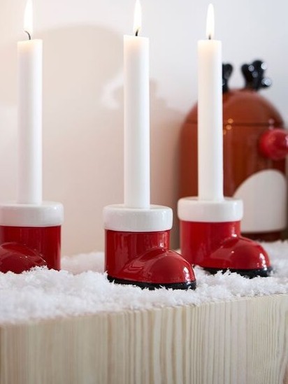 red boots shaped candle holders are on wooden shelve
