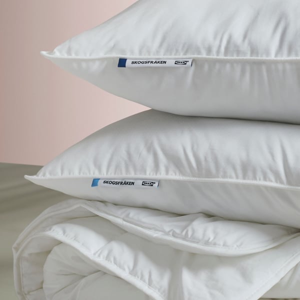 A low SKOGSFRÄKEN pillow stacked up between a high SKOGSFRÄKEN pillow and a folded FJÄLLARNIKA duvet with no cover on.