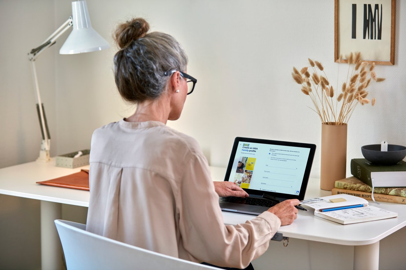 You can see a woman sitting at a desk in front of her laptop with the IKEA website open.