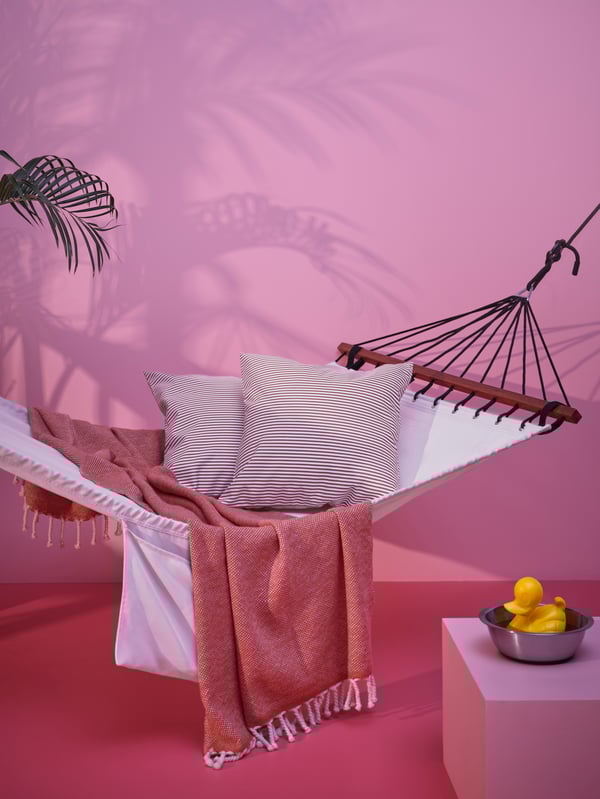 A hammock with various pillows and throws laid out on it