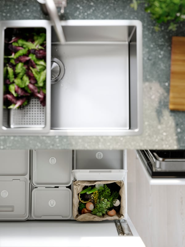 A VRESJĂ–N inset sink with one bowl has a colander with lettuce in it and waste sorting bins can be seen in the drawer below.