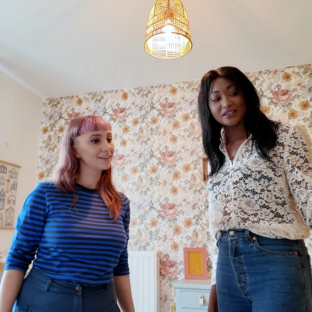 Une collaboratrice IKEA à côté d'une femme dans une chambre au papier peint fleuri