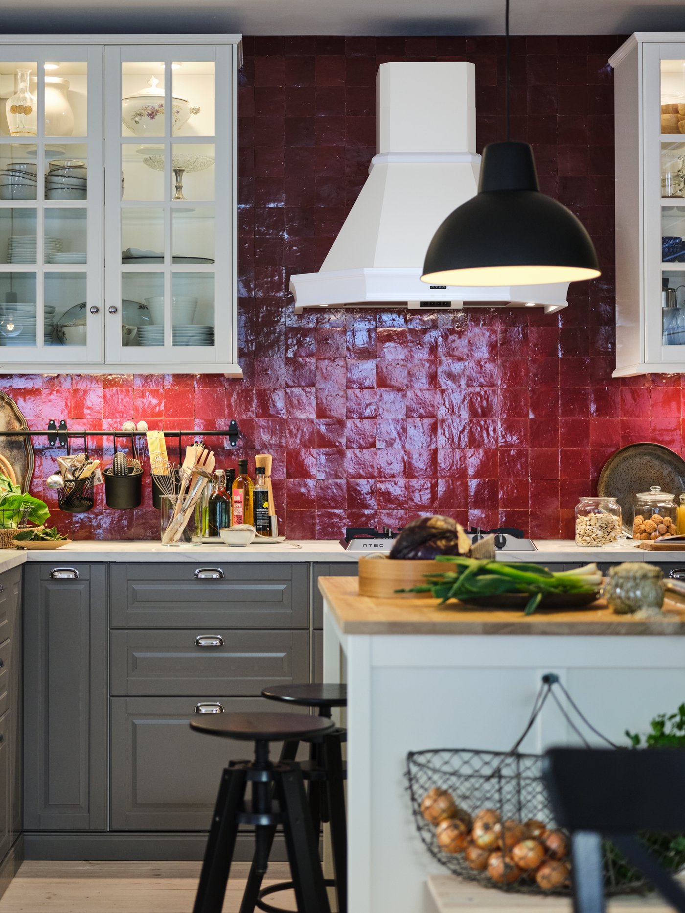 Cocina con un armario bajo para fregadero con tres frentes y dos cajones, una isla de cocina, una lámpara de techo y taburetes altos.