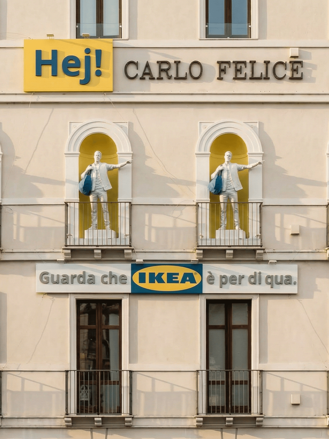 Immagine di un edificio con la scritta in alto "Hej Carlo Felice". Sulla facciata ci sono due archi con all’interno le statue di due collaboratori IKEA, con la borsa blu FRAKTA sulla spalla. 