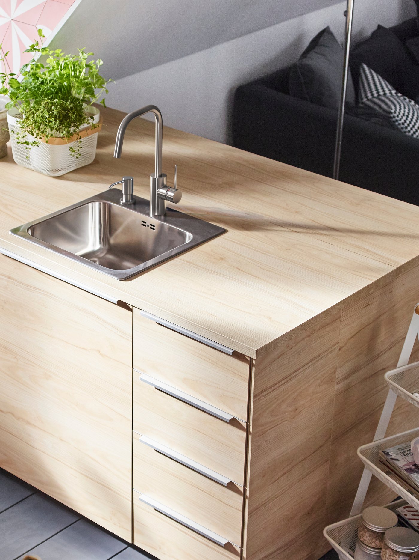 Detalle de una encimera beige hecha de tablón de conglomerado y laminado sobre un frente de cajón beige en una cocina moderna.