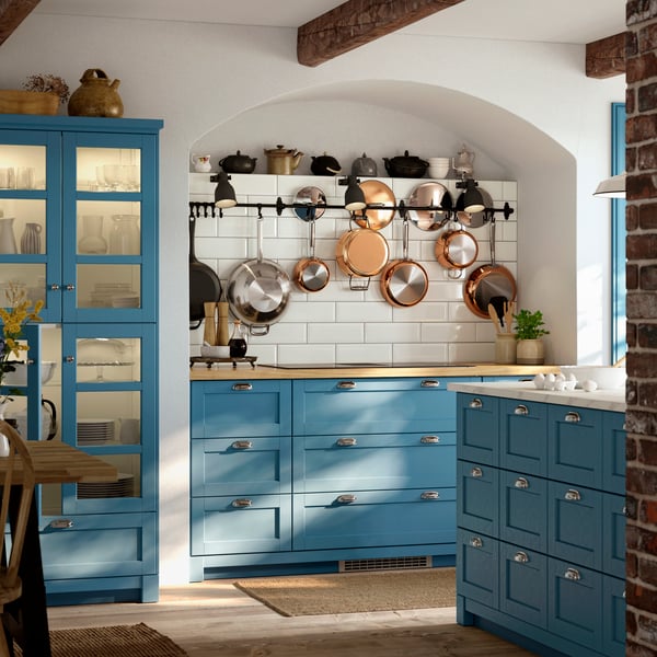 A SEKTION kitchen with fronts in LERHYTTAN blue has large windows, a kitchen island with drawers and a dining table.